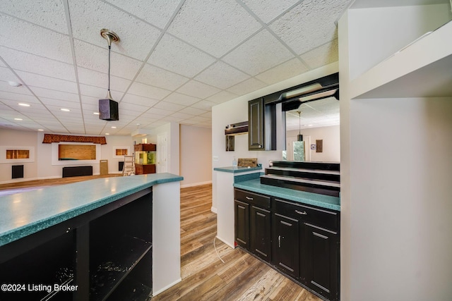 kitchen with a drop ceiling, light hardwood / wood-style flooring, and decorative light fixtures