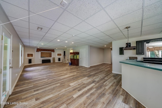 unfurnished living room with hardwood / wood-style floors, a healthy amount of sunlight, and a drop ceiling