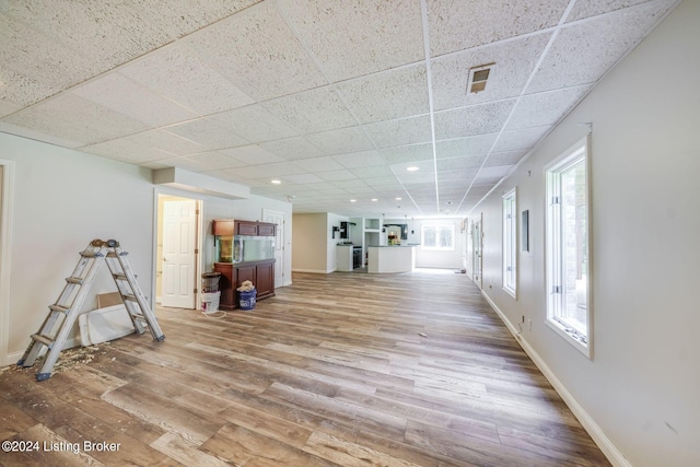 interior space featuring light hardwood / wood-style floors, a paneled ceiling, and a healthy amount of sunlight