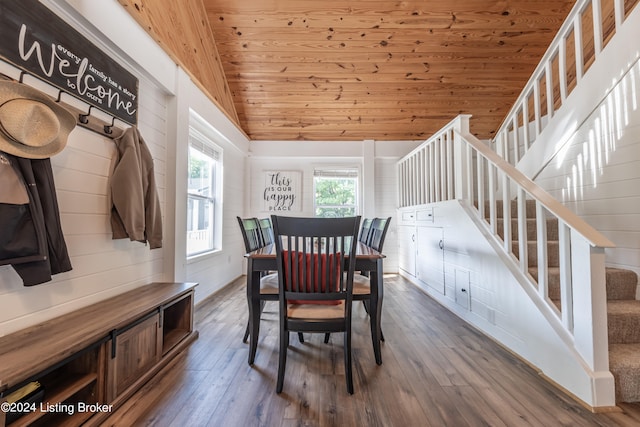 dining space with hardwood / wood-style flooring, lofted ceiling, wood ceiling, and wood walls