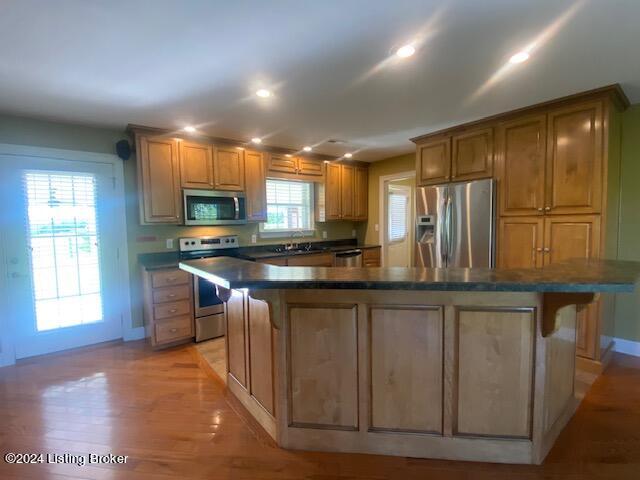 kitchen with sink, light hardwood / wood-style flooring, a kitchen island, and appliances with stainless steel finishes