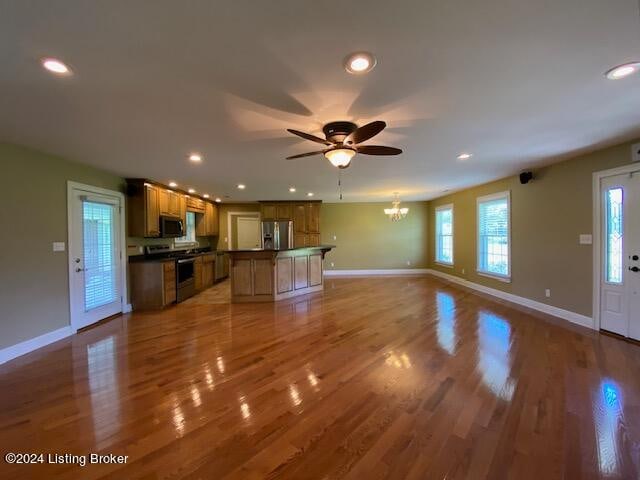 unfurnished living room featuring light hardwood / wood-style flooring and ceiling fan with notable chandelier