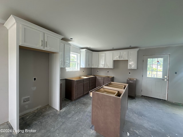 kitchen with concrete flooring, white cabinets, and a center island