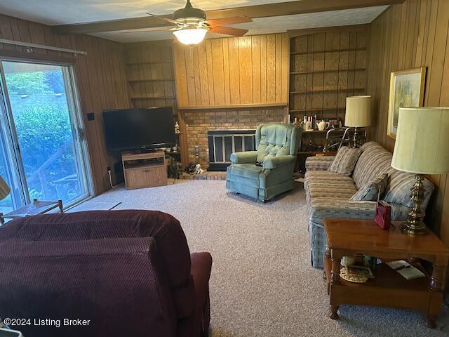 living room featuring built in shelves, a fireplace, light carpet, and wood walls