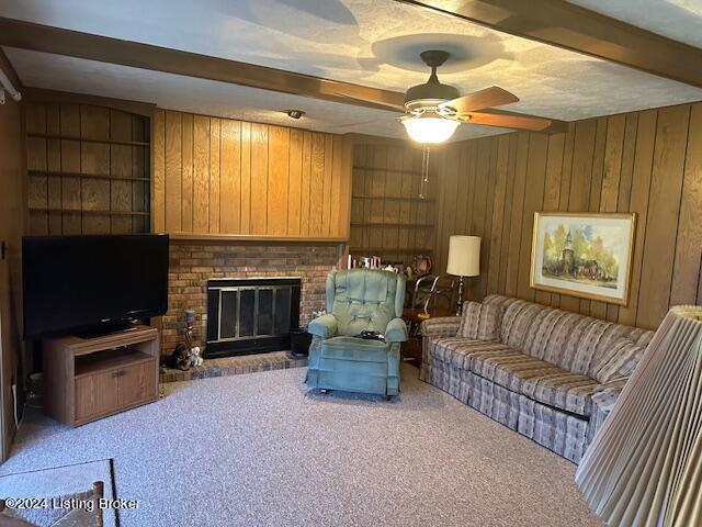 living room featuring a fireplace, beam ceiling, carpet floors, and wood walls