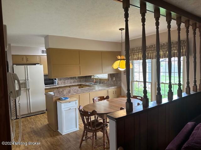 kitchen with tasteful backsplash, hanging light fixtures, a kitchen island, white fridge with ice dispenser, and hardwood / wood-style floors