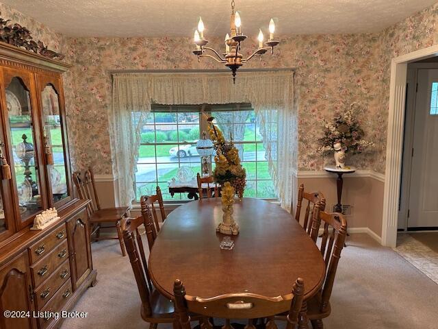 dining area featuring an inviting chandelier, light colored carpet, and a textured ceiling