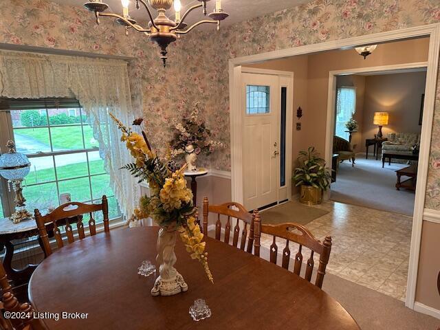 carpeted dining room with an inviting chandelier