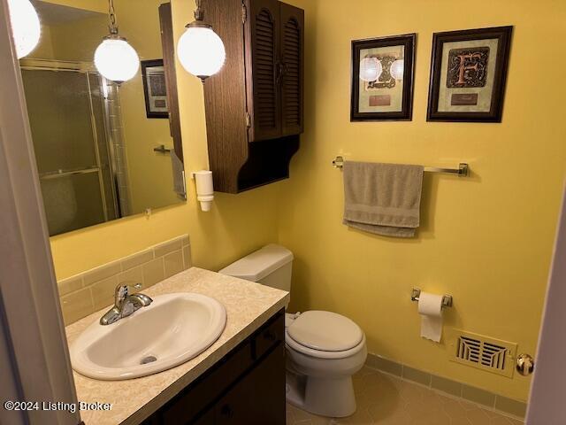 bathroom with vanity, toilet, tile patterned flooring, and a shower with door