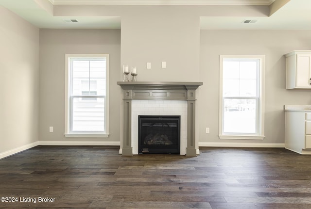 unfurnished living room with crown molding, dark hardwood / wood-style floors, a raised ceiling, and a brick fireplace