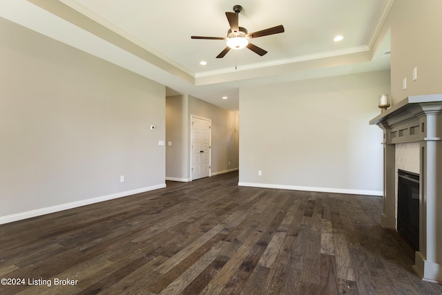 unfurnished living room with dark wood-type flooring, ornamental molding, a raised ceiling, and a tile fireplace