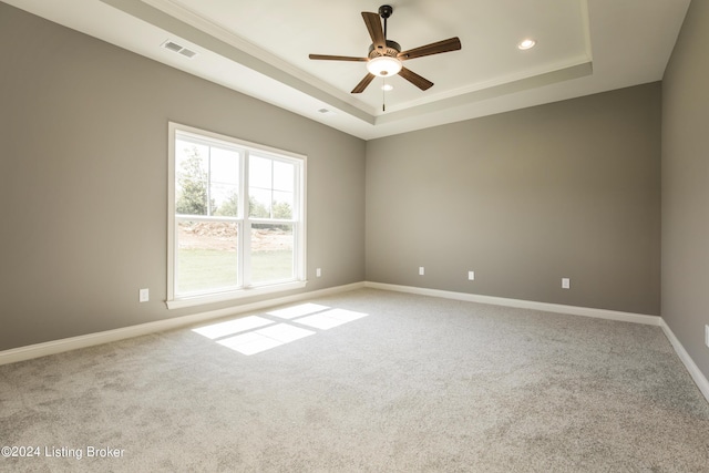 carpeted spare room featuring ceiling fan and a raised ceiling