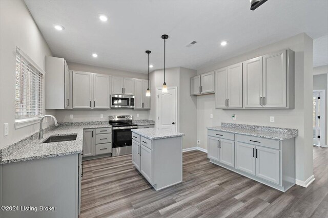 kitchen with stainless steel appliances, a kitchen island, light hardwood / wood-style floors, and sink