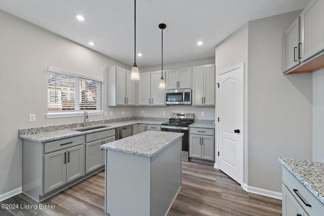 kitchen featuring a kitchen island, sink, stainless steel appliances, and dark wood-type flooring