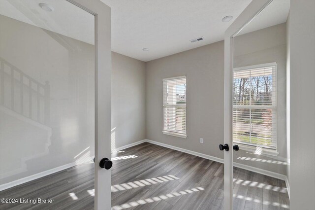 empty room with a wealth of natural light, french doors, and dark hardwood / wood-style floors