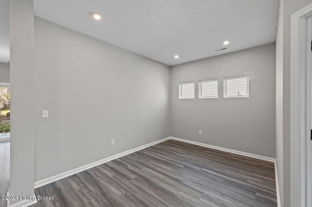 unfurnished bedroom featuring a textured ceiling and dark hardwood / wood-style floors