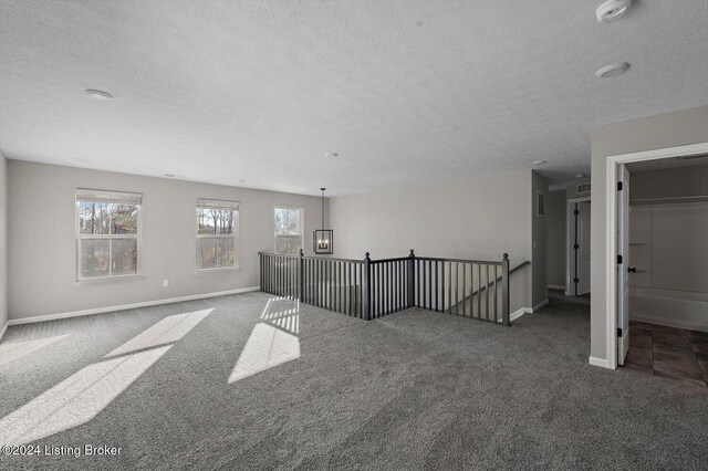 carpeted spare room featuring a textured ceiling and a notable chandelier