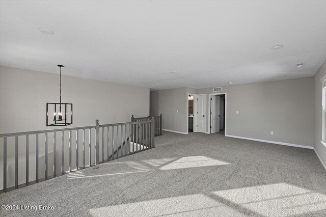 carpeted empty room with a notable chandelier