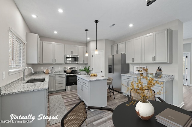 kitchen featuring pendant lighting, a center island, sink, light hardwood / wood-style floors, and stainless steel appliances