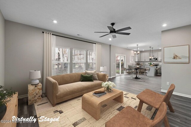 living room with ceiling fan with notable chandelier, a textured ceiling, and light hardwood / wood-style flooring