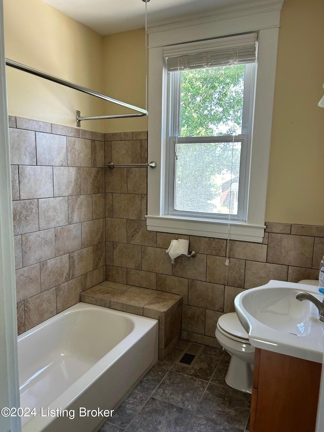 full bathroom featuring vanity, tiled shower / bath combo, tile walls, tile patterned flooring, and toilet