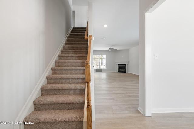 staircase with ceiling fan and wood-type flooring