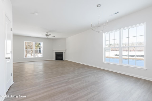 unfurnished living room with ceiling fan with notable chandelier and light wood-type flooring