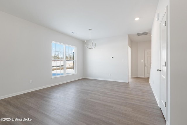 unfurnished room with a notable chandelier and hardwood / wood-style flooring