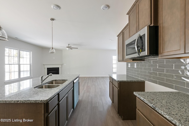 kitchen with decorative backsplash, stainless steel appliances, a kitchen island with sink, dark wood-type flooring, and sink