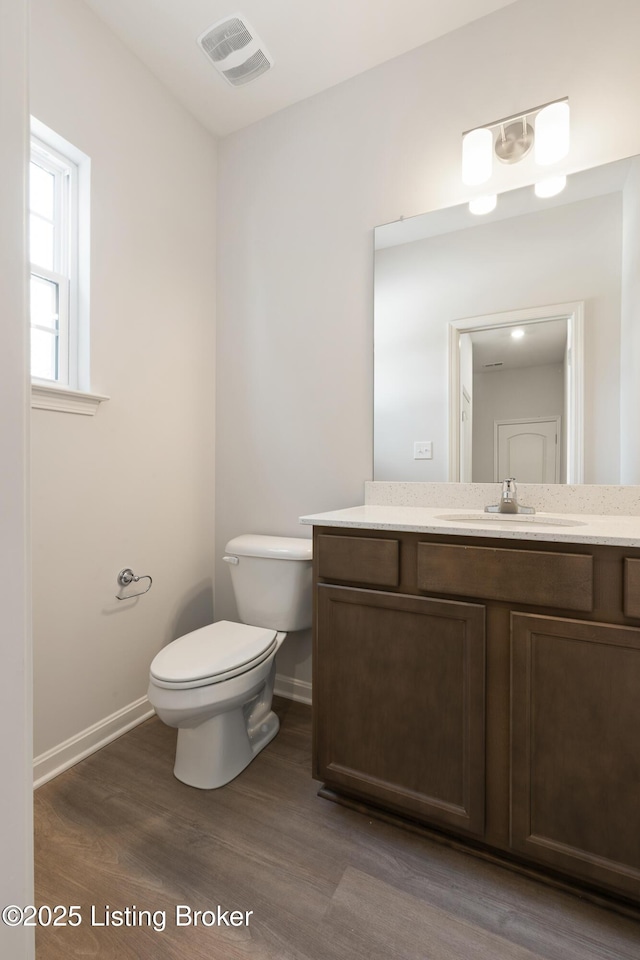 bathroom featuring wood-type flooring, vanity, and toilet