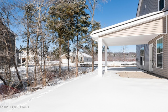 yard covered in snow featuring a carport