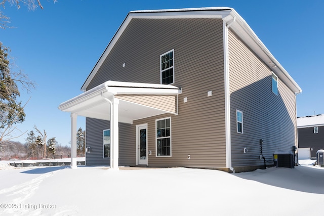 snow covered back of property with central AC