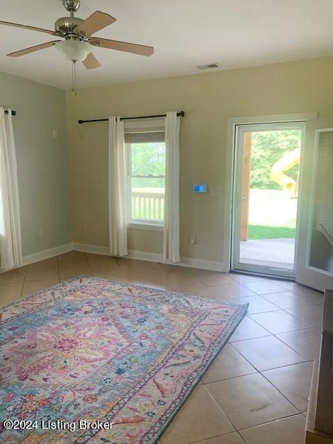 tiled empty room featuring a wealth of natural light and ceiling fan