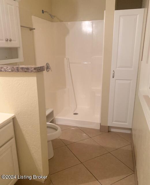 bathroom featuring a shower, vanity, tile patterned floors, and toilet