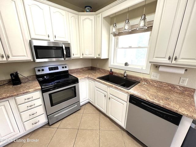 kitchen featuring stainless steel appliances, hanging light fixtures, sink, and white cabinets