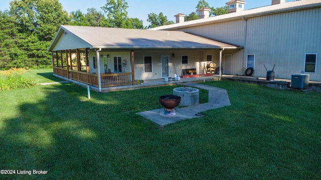 back of property featuring cooling unit, a lawn, and an outdoor fire pit