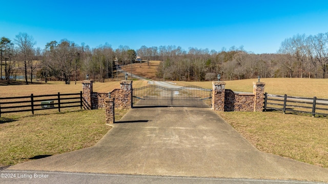 view of gate featuring a rural view and a lawn