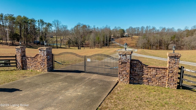 view of gate featuring a rural view and a lawn