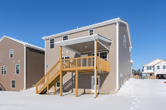 snow covered rear of property featuring a deck