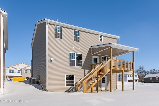 snow covered house featuring central AC unit and a deck