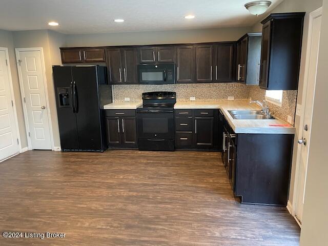 kitchen featuring sink, tasteful backsplash, dark brown cabinetry, wood-type flooring, and black appliances