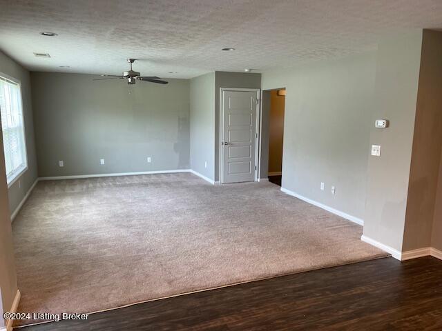 unfurnished room with ceiling fan, a textured ceiling, and dark colored carpet