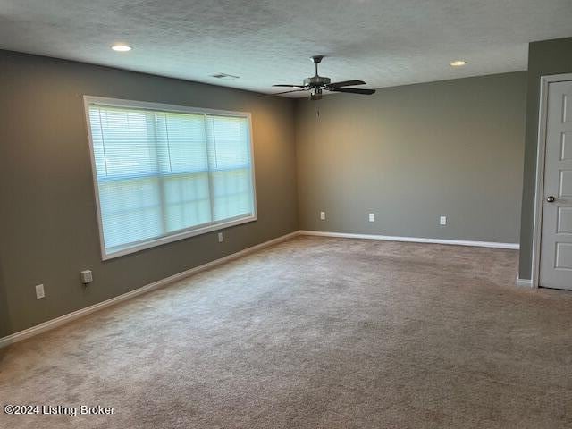 carpeted spare room with ceiling fan and a textured ceiling