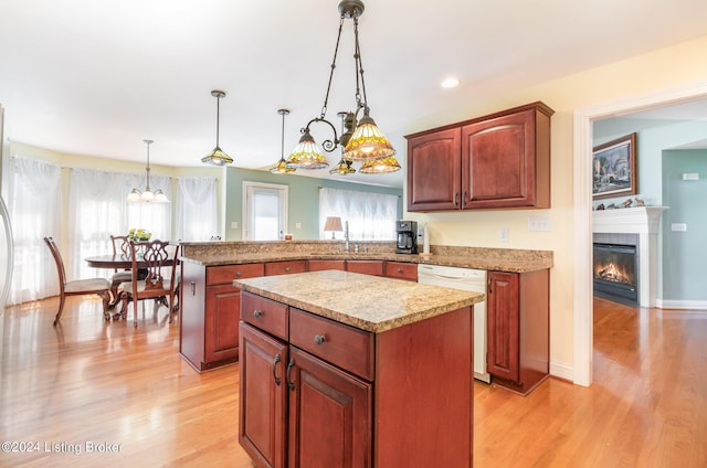 kitchen featuring decorative light fixtures, sink, a center island, white dishwasher, and kitchen peninsula