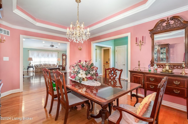 dining space with crown molding, a tray ceiling, and light hardwood / wood-style flooring