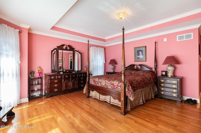 bedroom featuring crown molding, hardwood / wood-style floors, and a tray ceiling