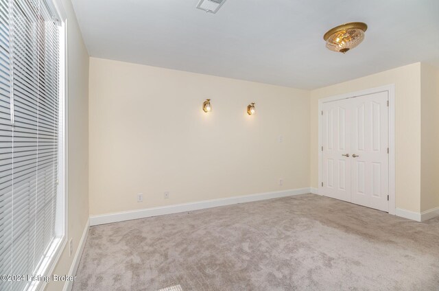 unfurnished bedroom featuring light colored carpet and a closet