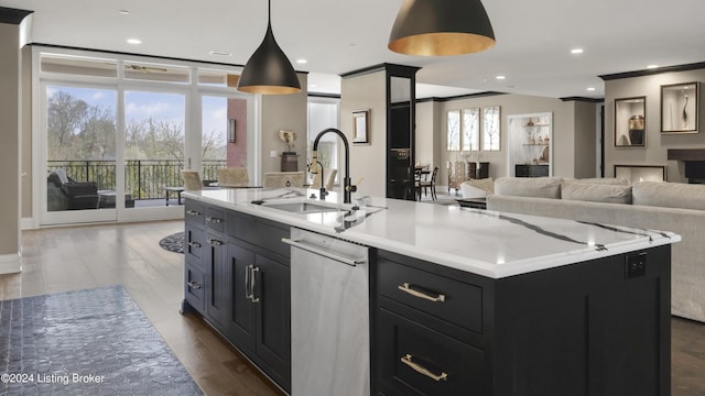 kitchen with light stone countertops, sink, a center island with sink, hardwood / wood-style floors, and hanging light fixtures