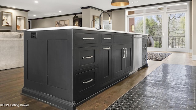 kitchen with dark hardwood / wood-style floors, sink, ornamental molding, and a kitchen island with sink