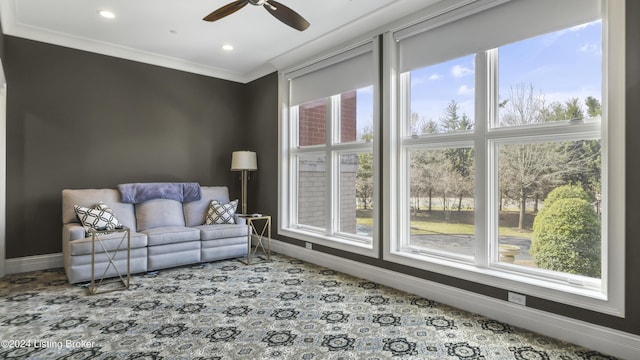 carpeted living room with a wealth of natural light, crown molding, and ceiling fan